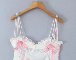 Detail of floral mini dress featuring pink bows, lace ruffles and thin shoulder straps