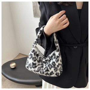 Detail of stylish leopard print plush handbag held by model in professional setting
