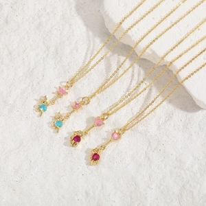 Close-up of gold necklaces with star and heart zircon pendants on a textured stone surface