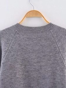 Close-up of grey knit cardigan featuring round neck and raglan sleeve texture details