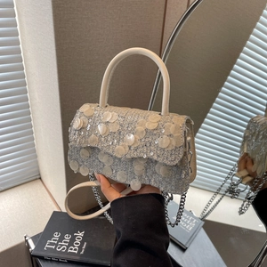 Close-up of sparkling silver sequin crossbody bag with chain strap and white handle