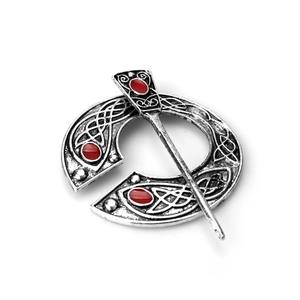 Detail of silver Celtic knot penannular brooch with three red oval gemstones on white background