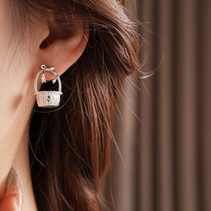 Close-up of silver bow basket earring with pearl details worn on model's ear