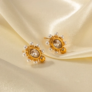 Vue détaillée de boucles d'oreilles ovales plaquées or 18K avec perles sur soie beige
