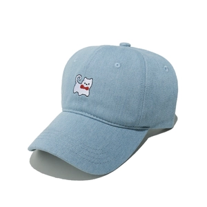 Detailed view of light blue denim baseball cap featuring cute white cat embroidery with red bow