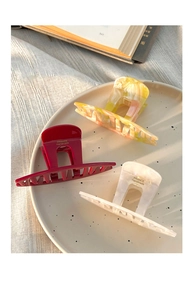 Detailed view of handmade acetate hair claws in red, marble yellow, and creamy white