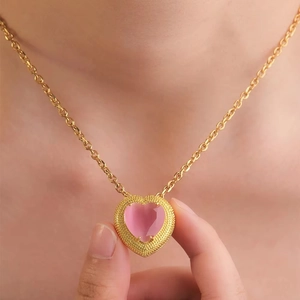 Pink heart-shaped pendant necklace in gold setting shown on neck with high light transparency