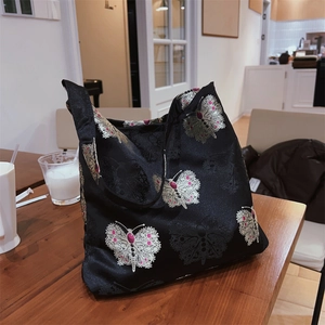 Detail of vintage jacquard tote bag with elegant butterfly pattern on wood table