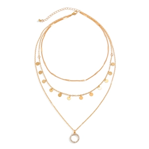 Close-up of golden multi-layer necklace with circular discs and rhinestone pendant