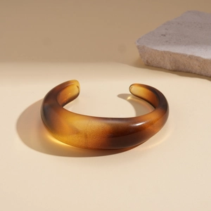Macro detail of amber resin cuff bracelet showing smooth texture and tortoiseshell finish