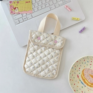 Detailed shot of floral quilted fabric mini tote bag with pink snap buttons on a desk