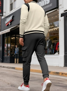 Rear view of off-white varsity jacket and grey cargo pants on a city street