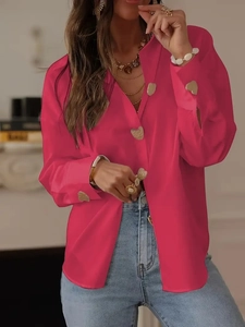 Close-up of golden heart-shaped buttons on vibrant magenta satin long-sleeve blouse