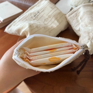 Detail of off-white woven cotton bag with zipper showing sanitary pads storage inside