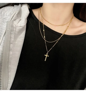 Close-up of golden triple-layered titanium steel necklace with cross pendant on model