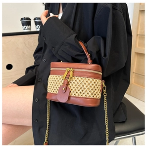 Fashionable woven box bag in brown and beige shown held by a model in a cafe setting