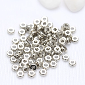 Silver metal donut spacer beads for DIY jewelry making displayed on white fabric