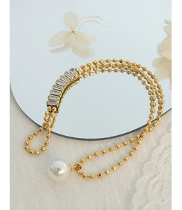 Macro shot of multi-layer gold beaded bracelet with rectangular crystals and large pearl
