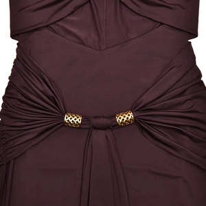 Détail de la taille découpée sur robe prune avec anneaux dorés et tissu plissé élégant