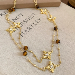 Macro shot of gold beaded chain with tiger eye stone and crystal cross flower charms