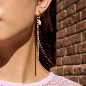 Orecchini lunghi a nappa in oro 18K con perla e zirconi indossati da una modella