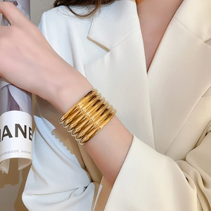 Detailed close-up of stacked gold pleated textured bangles with polished metallic finish