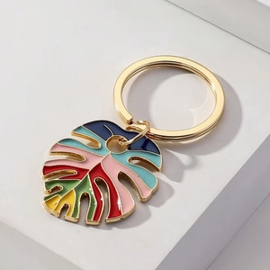 Macro shot of colorful enamel monstera leaf keychain with gold metal plating