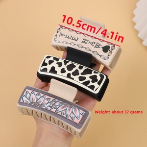 Detailed size view of western style hair claws with cow print and sunflower patterns