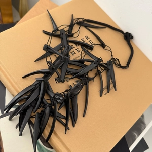 Detailed view of black gothic spiked necklace featuring layered resin pendants on woven rope