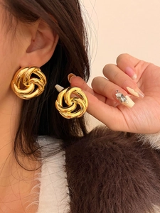 Close-up of elegant gold knotted hollow flower earrings worn by a female model
