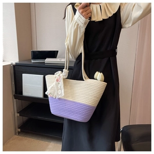 Close-up of a woven tote bag in purple and cream with decorative lace ribbon scarf