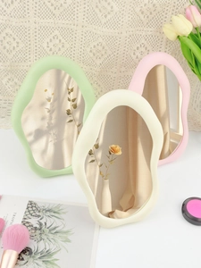 Three wavy cloud makeup mirrors in mint, cream, and pink on a lace vanity table