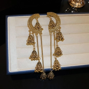 Gros plan de boucles d'oreilles bohèmes dorées vintage avec pompons et clochettes
