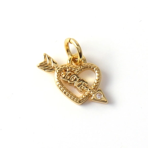 Macro detail of gold plated heart pendant with LOVE engraving and tiny zircon stone