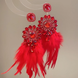 Détail de boucles d'oreilles en cristal rouge avec de longs pompons en plumes souples