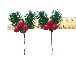 Close-up of artificial pine needles with red berries for Christmas DIY decor on a white background