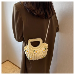 Detail of handmade knit shell bag with daisy flowers and elegant pearl strap