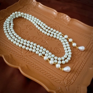 Macro detail of multi-layer pearl necklace with teardrop pendants and golden clasp