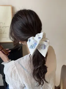 Macro detail of white silk hair scrunchie with blue ocean shell embroidery textures