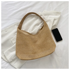 Top view of a khaki woven beach bag with shoulder strap next to a smartphone