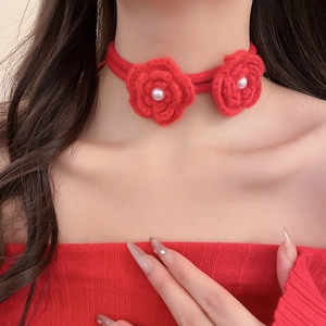 Close-up of red crochet flower choker featuring central pearls and woven strap details