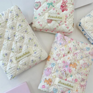 Detailed view of quilted cotton pouches with floral and rabbit patterns and logo label