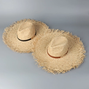 Close-up of raffia sun hats with frayed edges, leather bands, and gold H-metal buckles