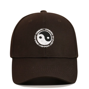 Detailed view of Yin Yang embroidery and white Swimming text on a brown cotton baseball cap