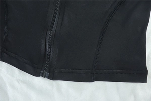 Detail of black sports vest showing durable resin zipper and high-density double stitching