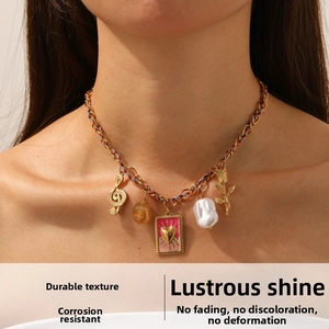 Detail of colorful charm necklace with pearl, heart, and musical note on woven chain