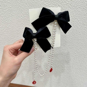 Close-up of velvet bow hair clips with long pearl chains and red Fu character pendants