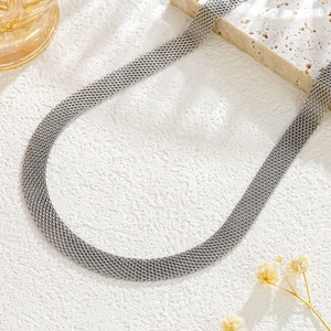 Close-up of silver woven mesh metal collar necklace on decorative stone background