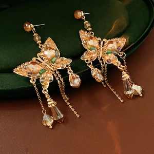 Vue macro des boucles d'oreilles papillon dorées avec cristaux sur velours vert