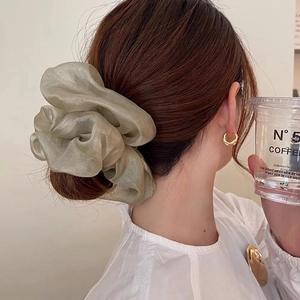 Champagne gold oversized silk scrunchie with metallic sheen on messy bun hairstyle